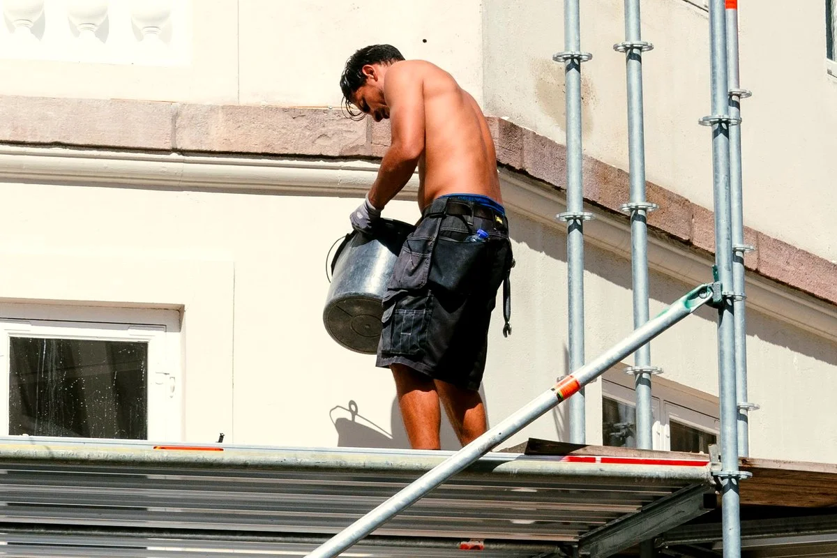 Ouvrier torse nu sur un echafaudage en plein soleil